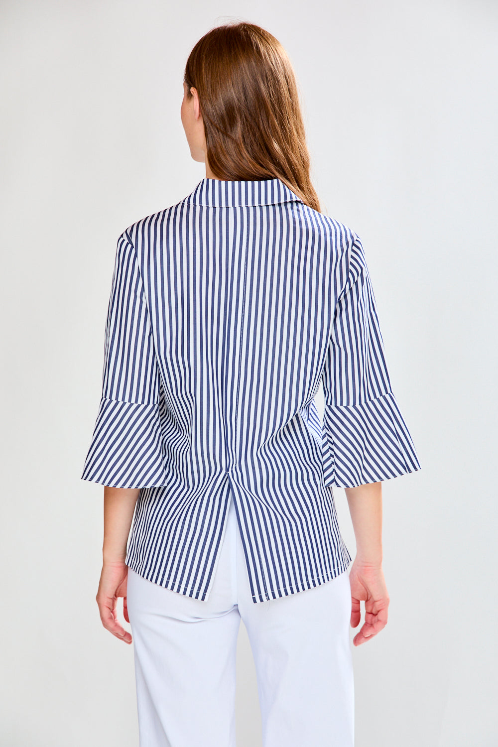 Woman wearing a blue and white striped shirt with a peplum waist on a plain background