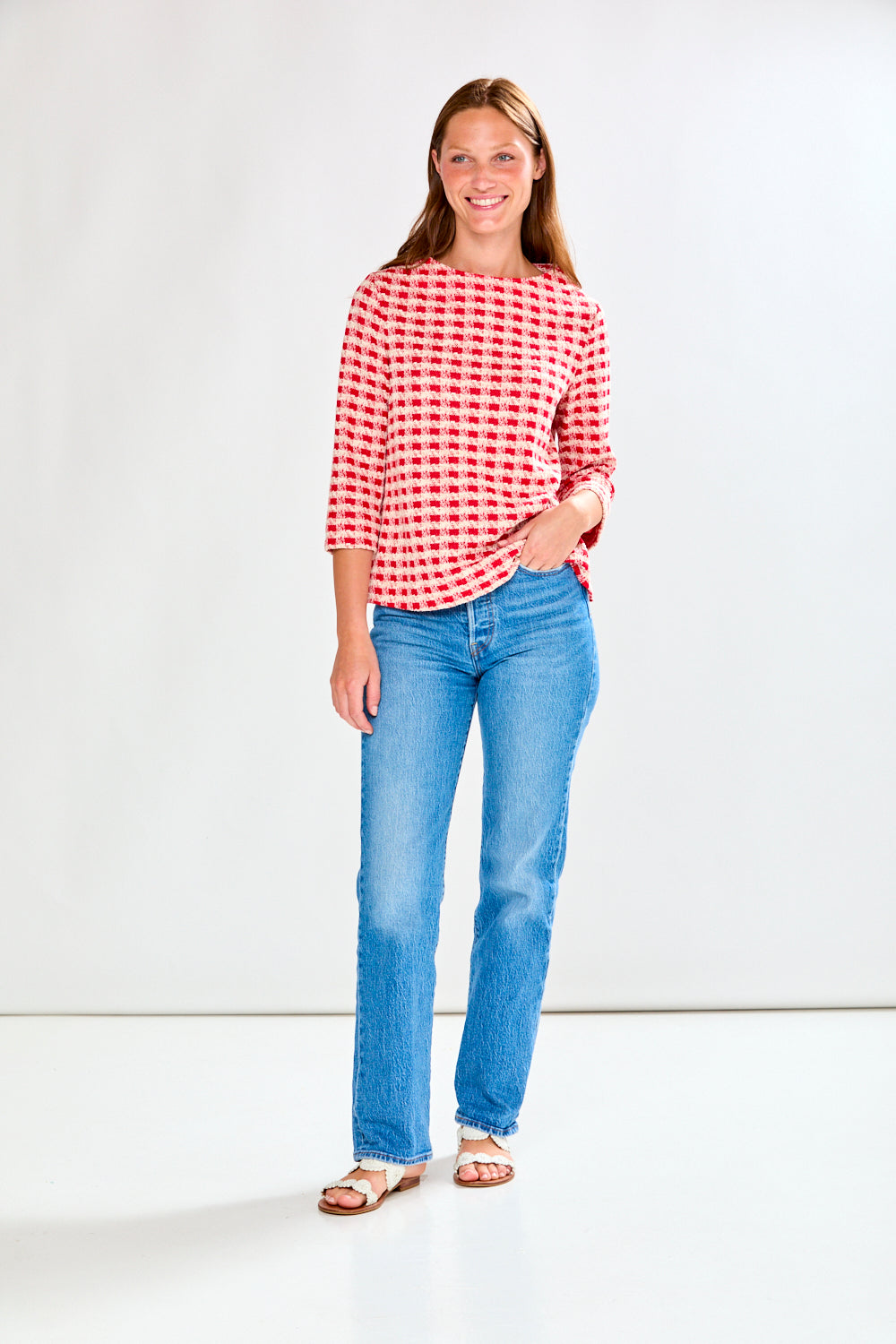 Woman wearing a red and white checkered shirt with blue jeans on a white background