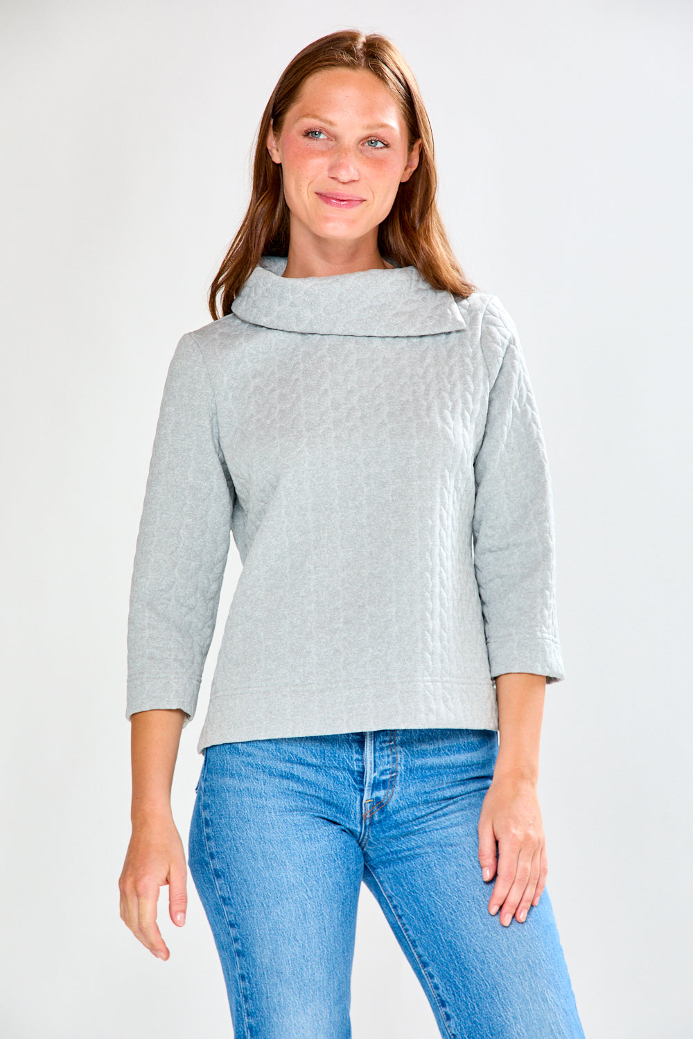 Woman wearing a gray sweater and blue jeans on a white background