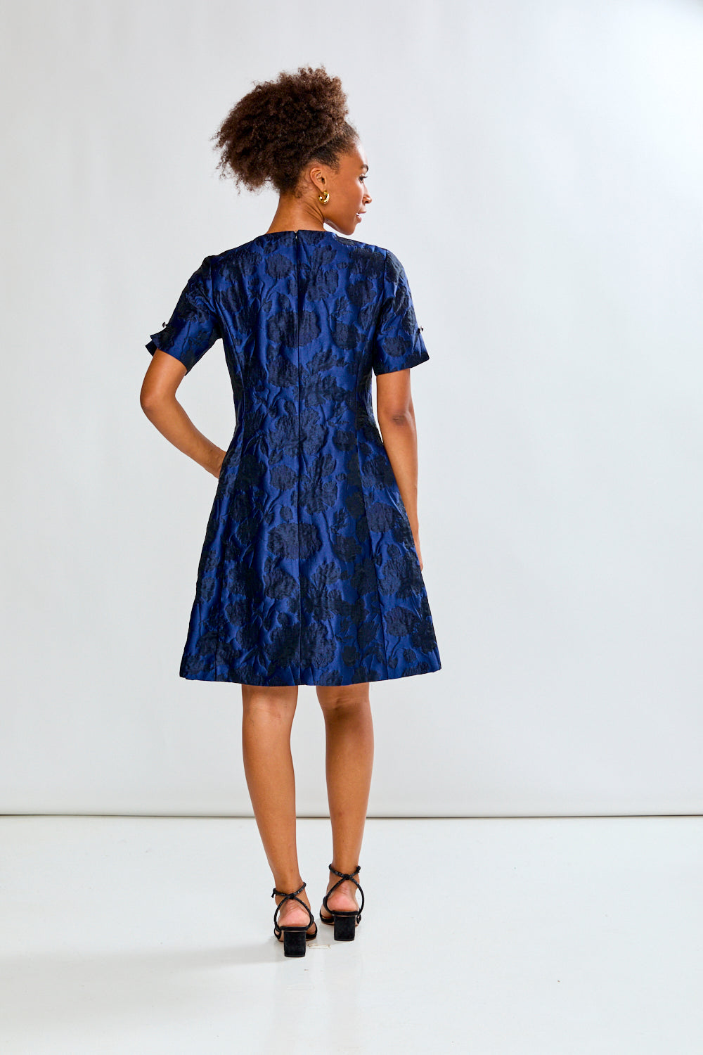 Woman wearing a blue patterned dress against a white background