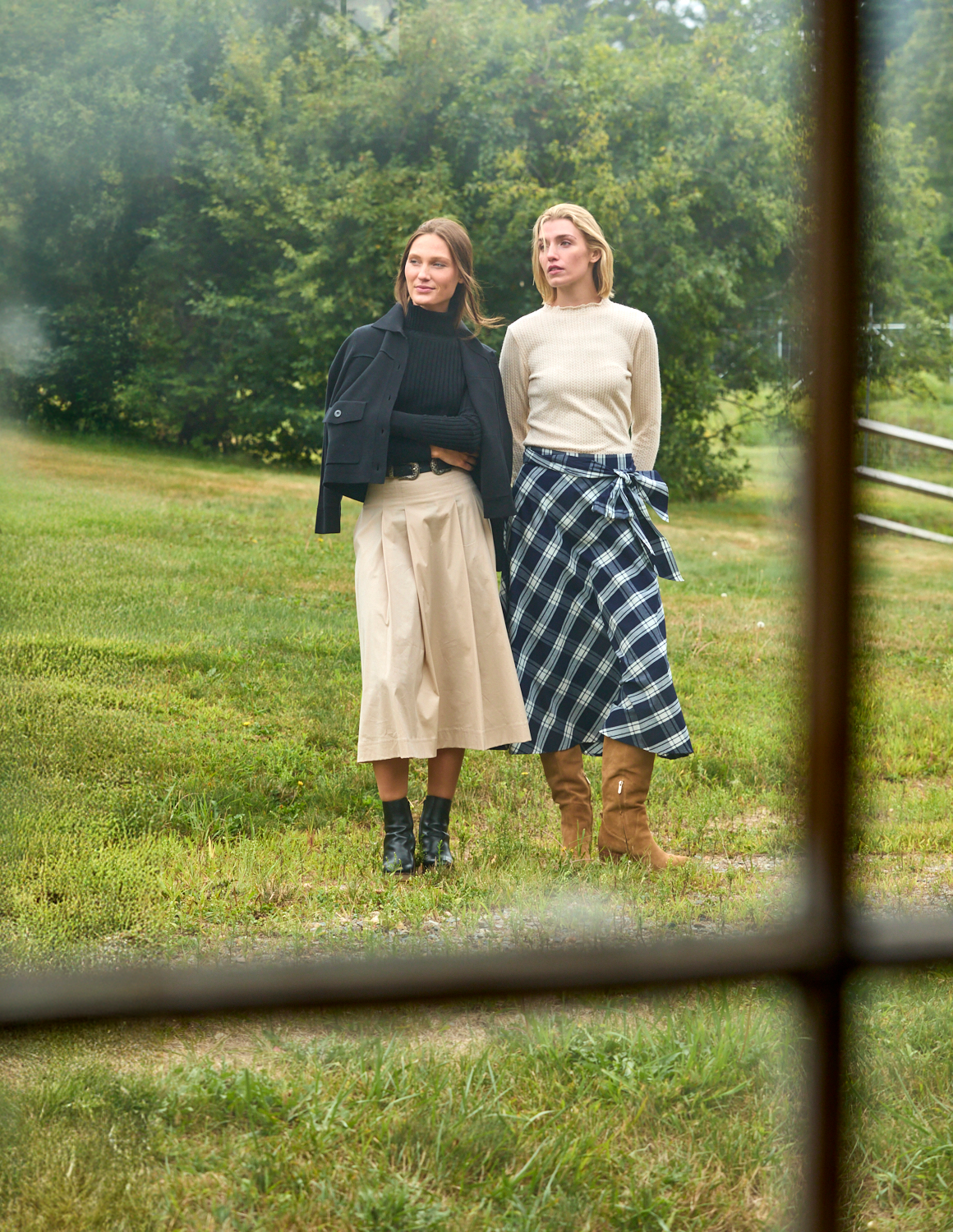 Two people photographed through a window outside on a farm