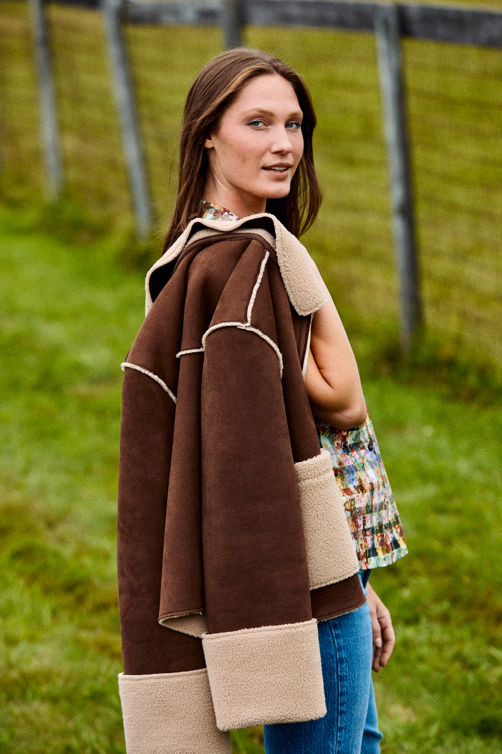 Woman wearing a brown and beige poncho in a grassy field