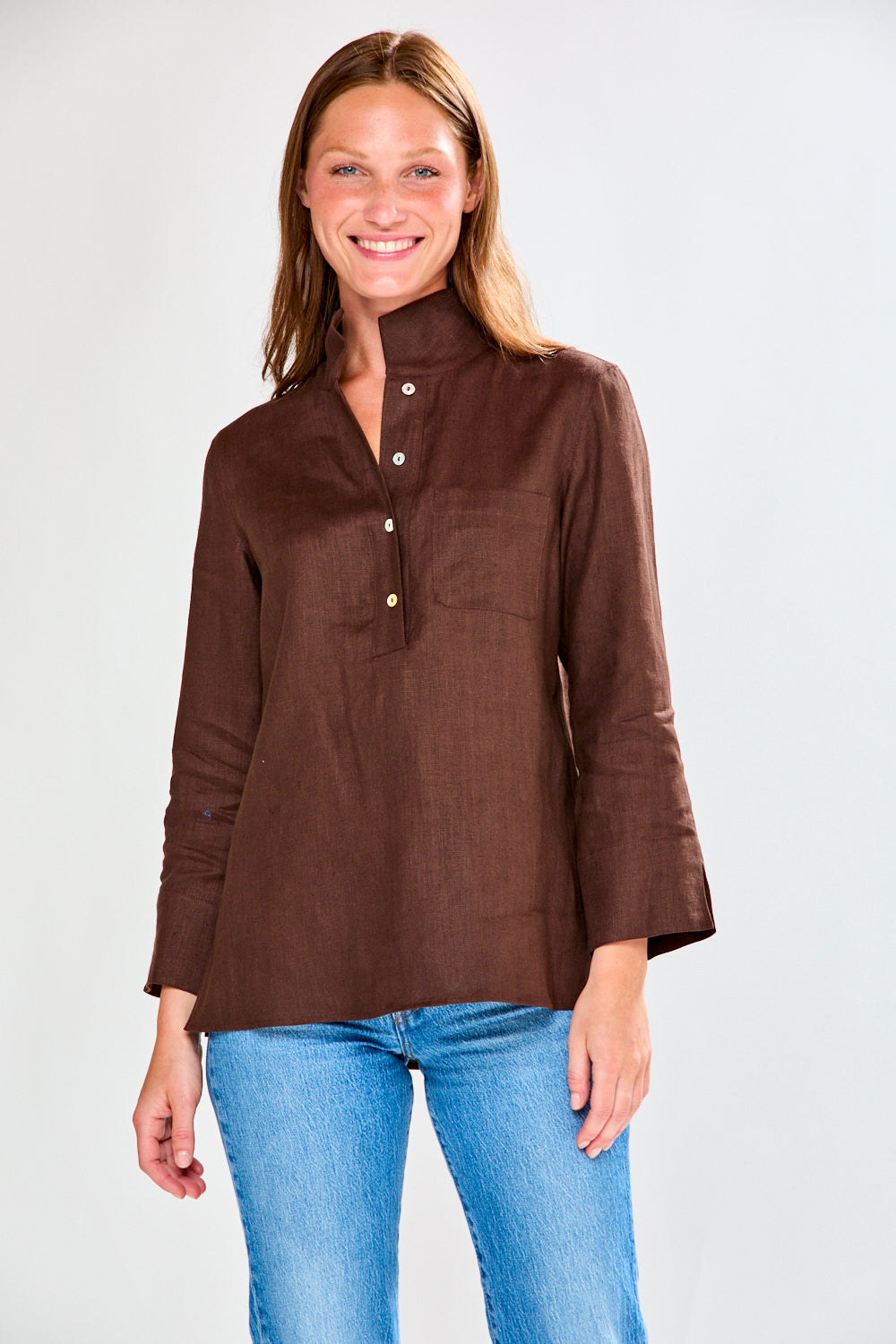 Woman wearing a brown blouse and blue jeans on a white background