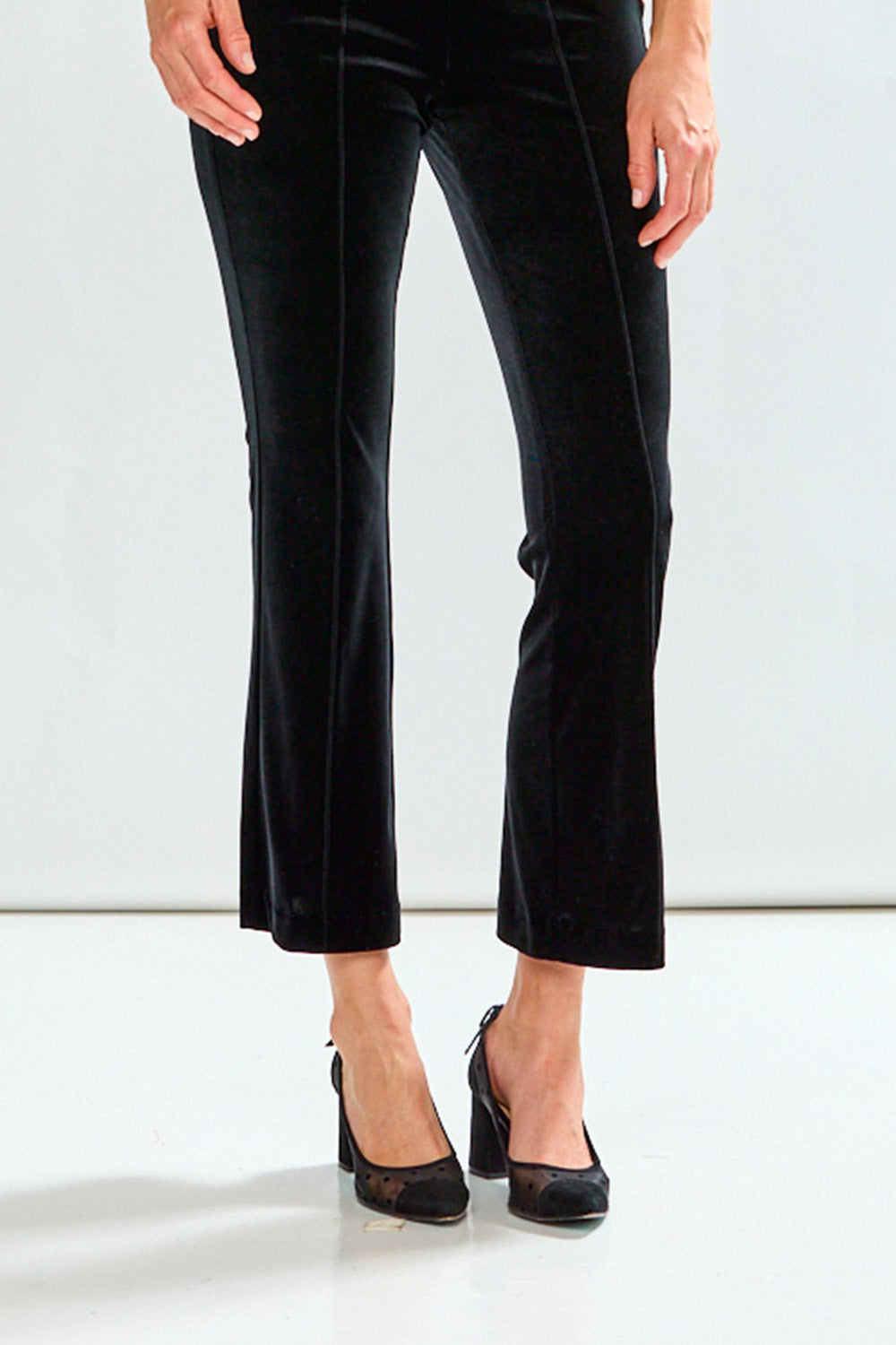 Black velvet pants worn by a person on a white background