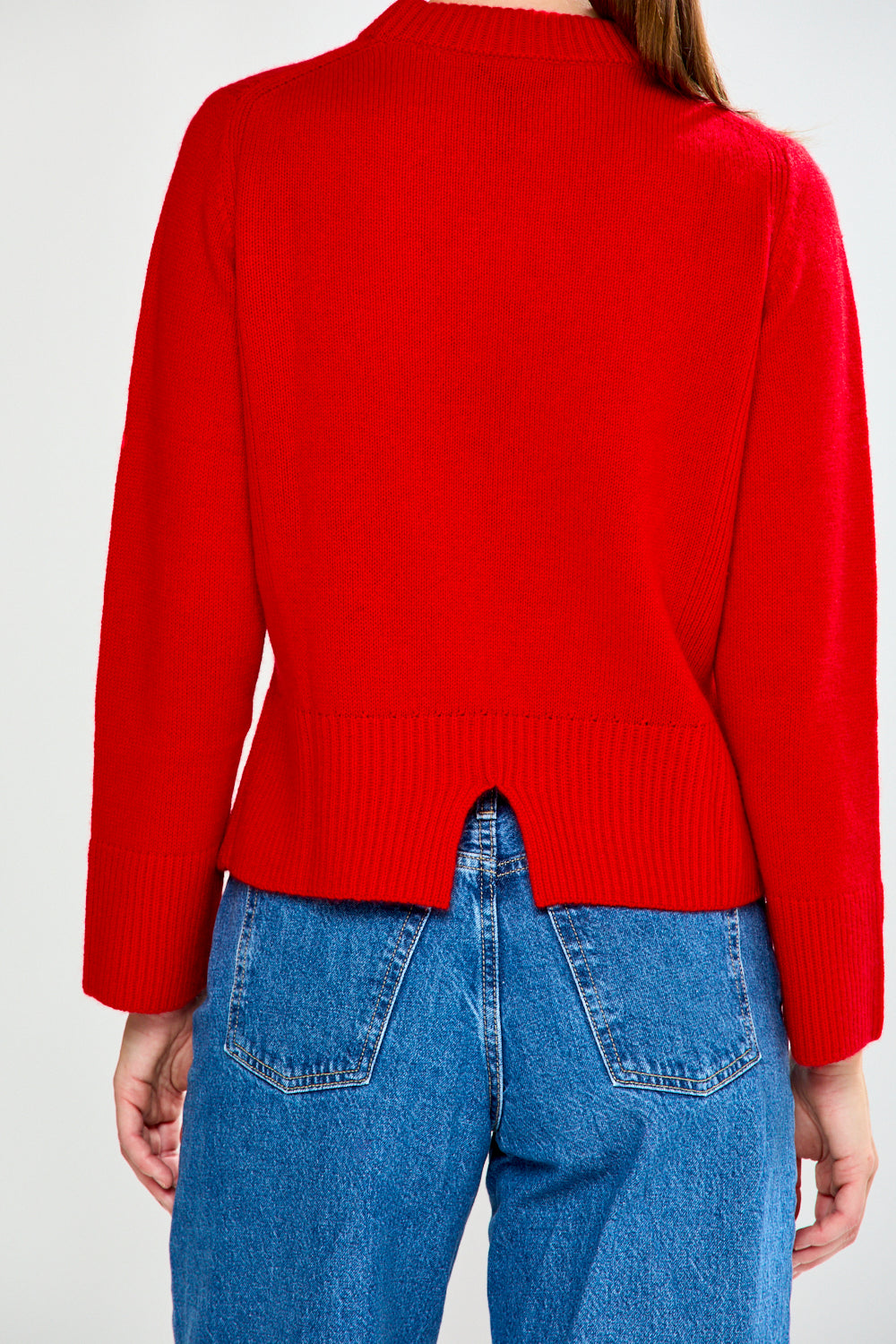 Woman wearing a red sweater and blue jeans on a white background