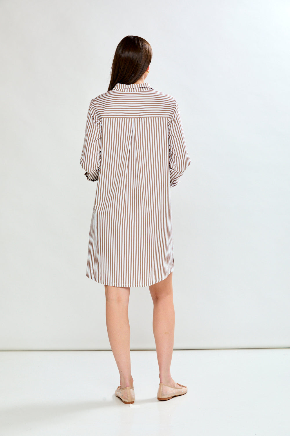 Woman wearing a striped dress standing against a white background