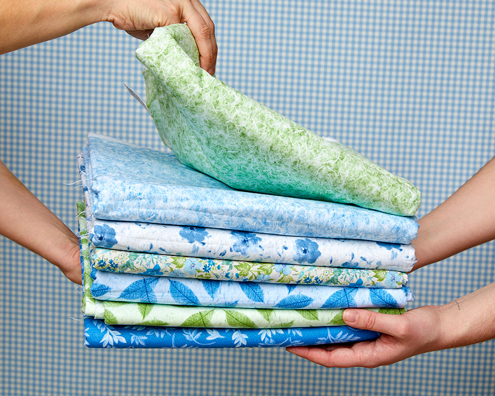 Two hands holding a stack of fabric