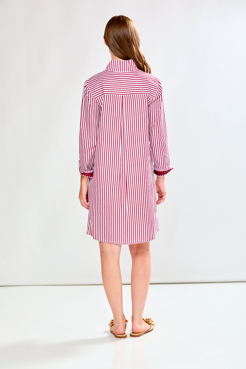 Woman wearing a raisin and white striped dress on a white background