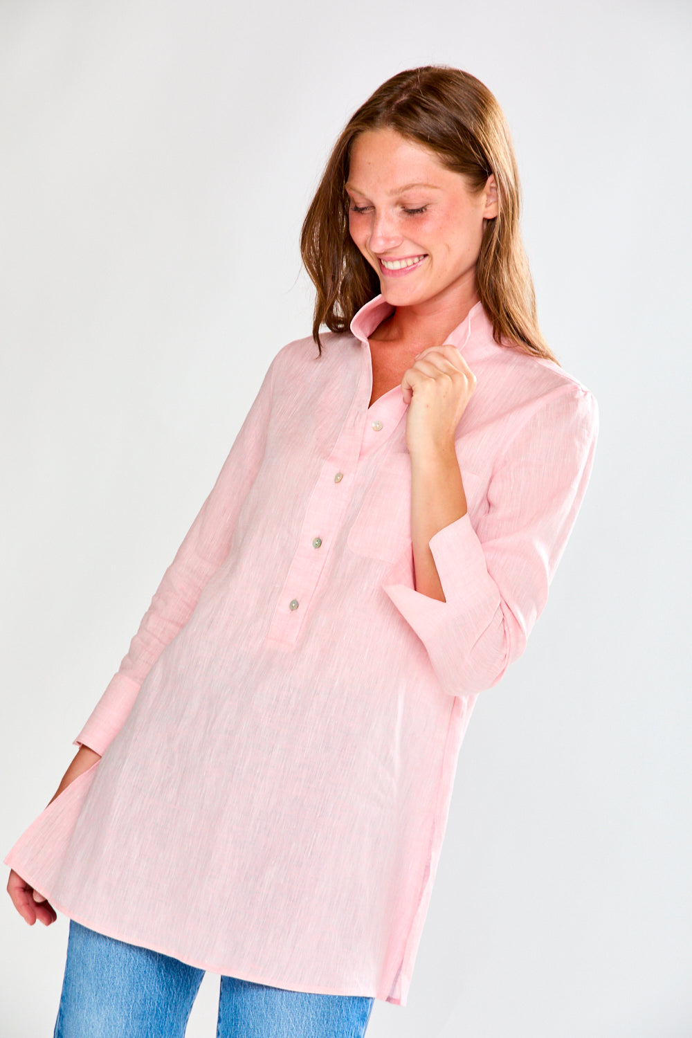 Woman wearing a light pink button-up shirt on a white background