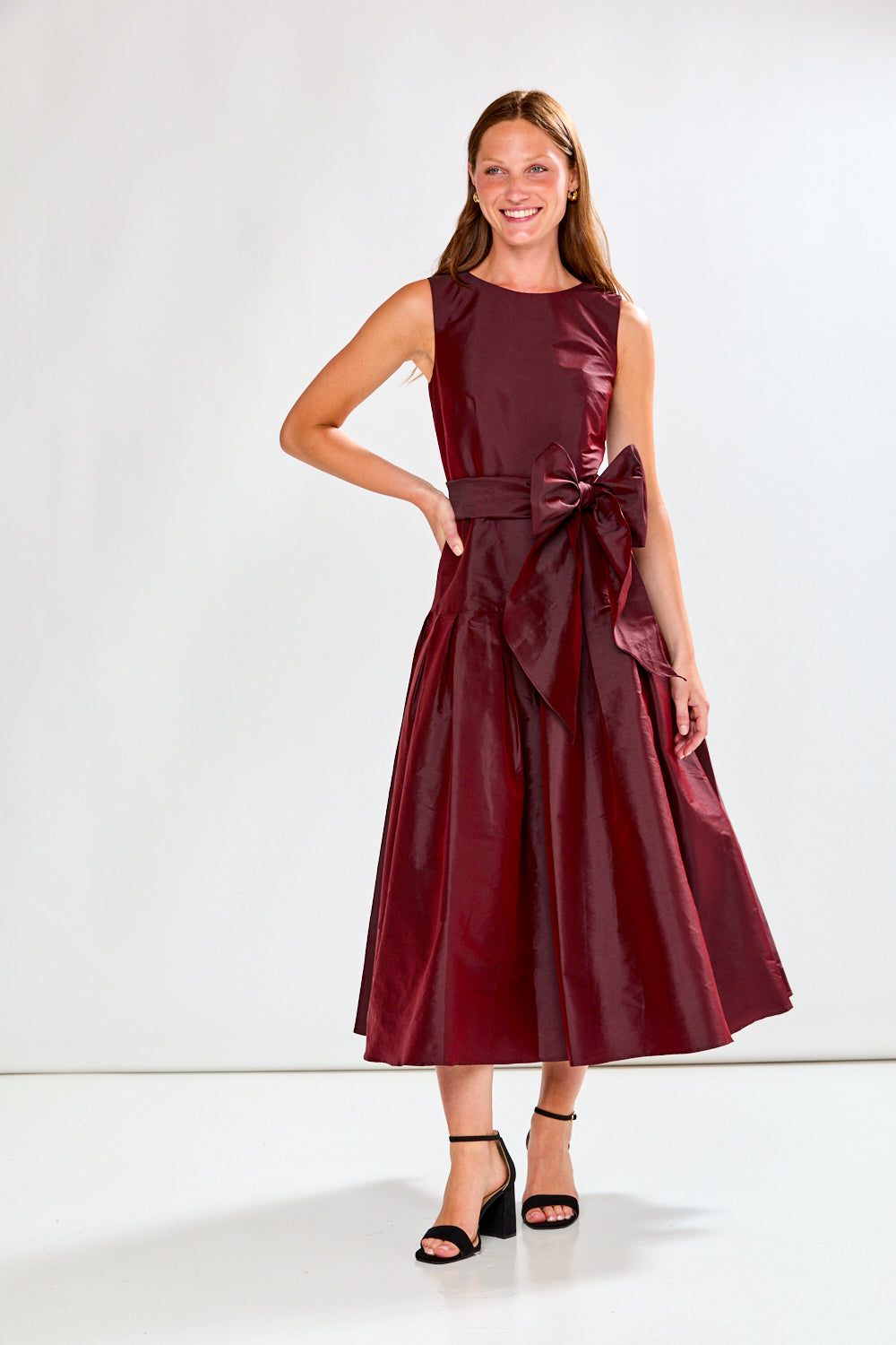 Woman wearing a burgundy dress with a bow detail on a white background