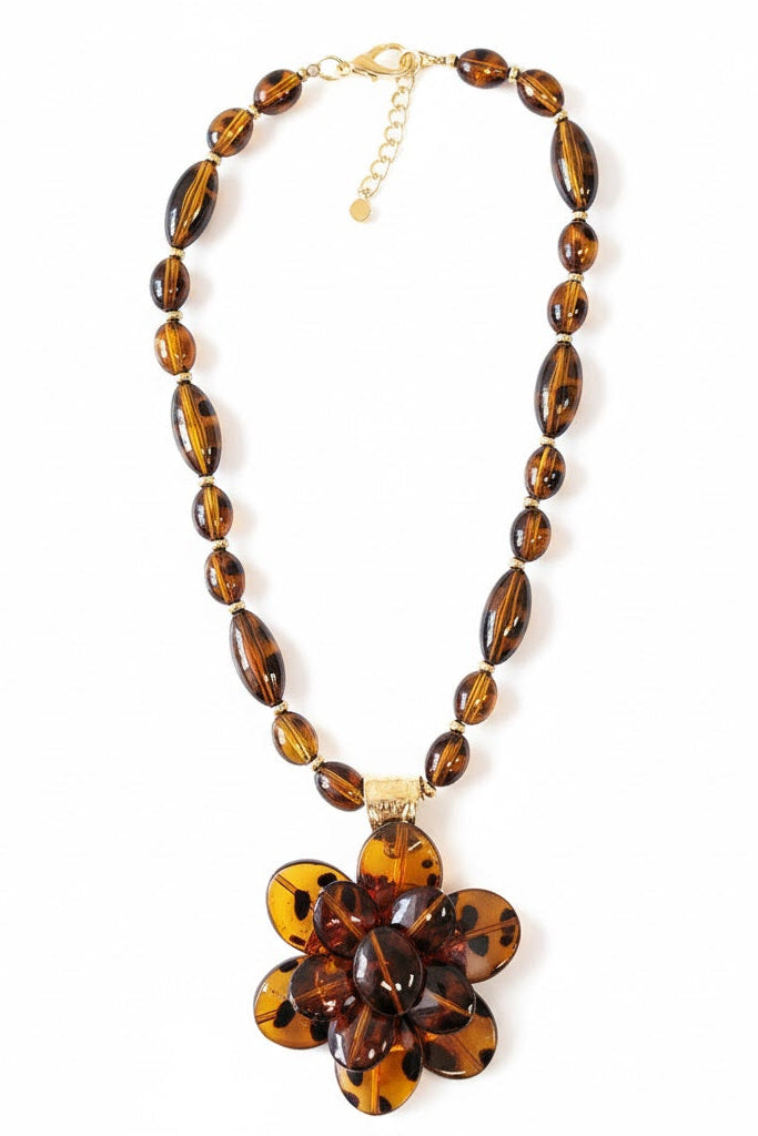 Necklace with brown beaded chain and flower-shaped pendant on a white background