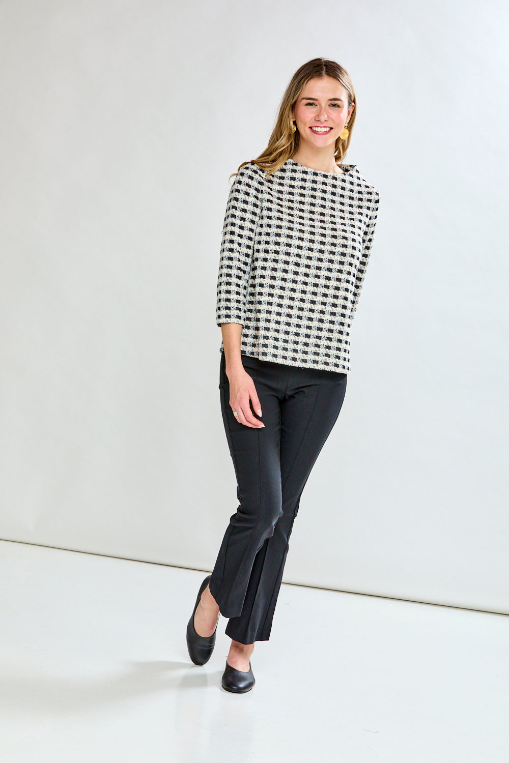 Woman wearing a black and white checkered blouse against a plain background