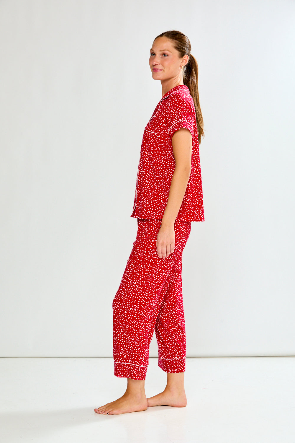 Woman wearing a red patterned pajama set on a white background