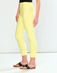 Person wearing bright yellow leggings and black sandals on a white background