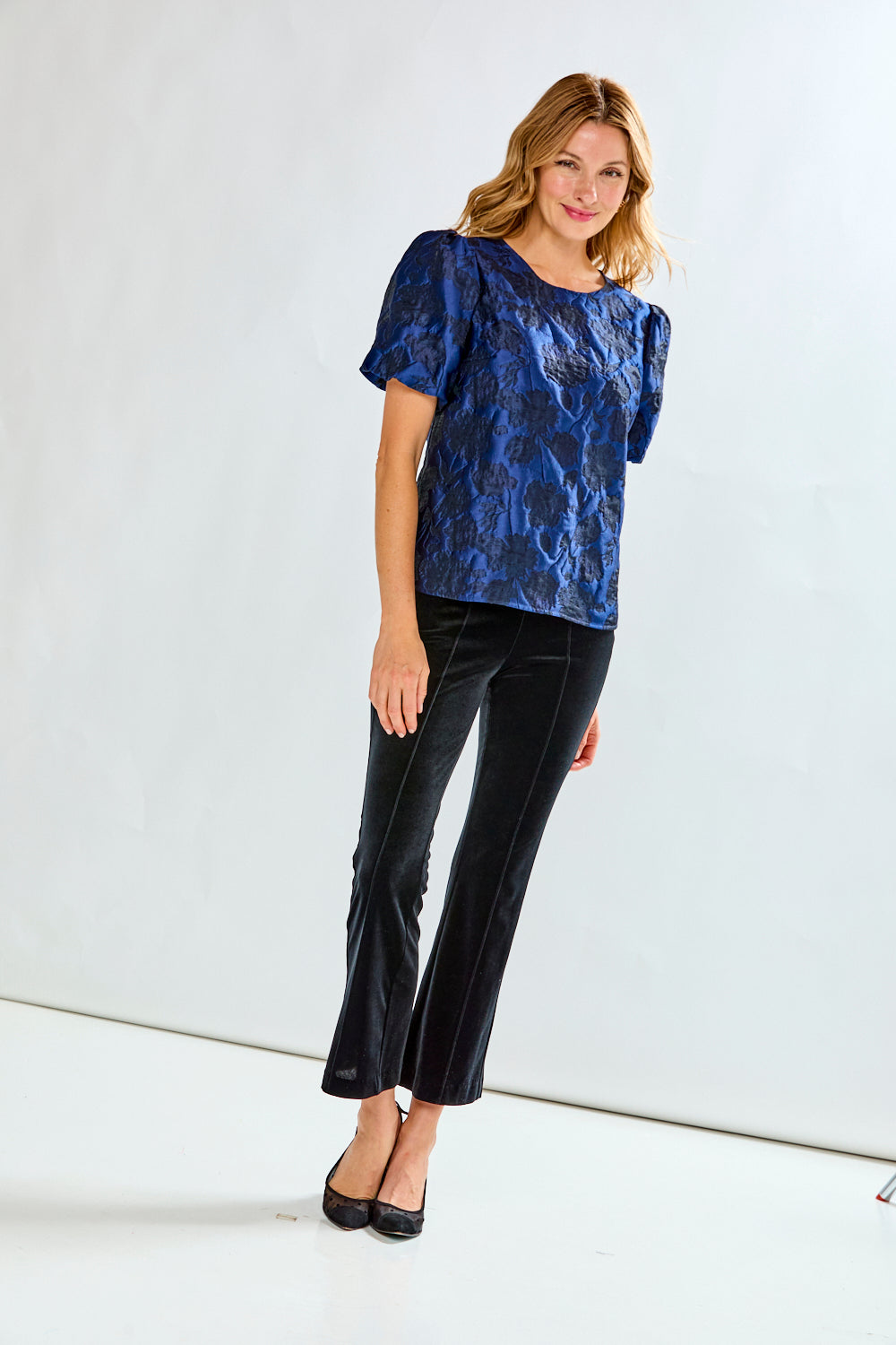 Black velvet pants worn by a person on a white background