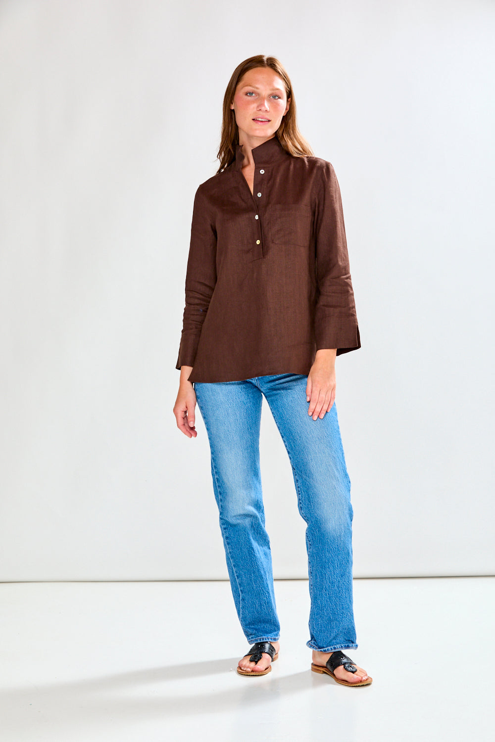 Woman wearing a brown blouse and blue jeans on a white background