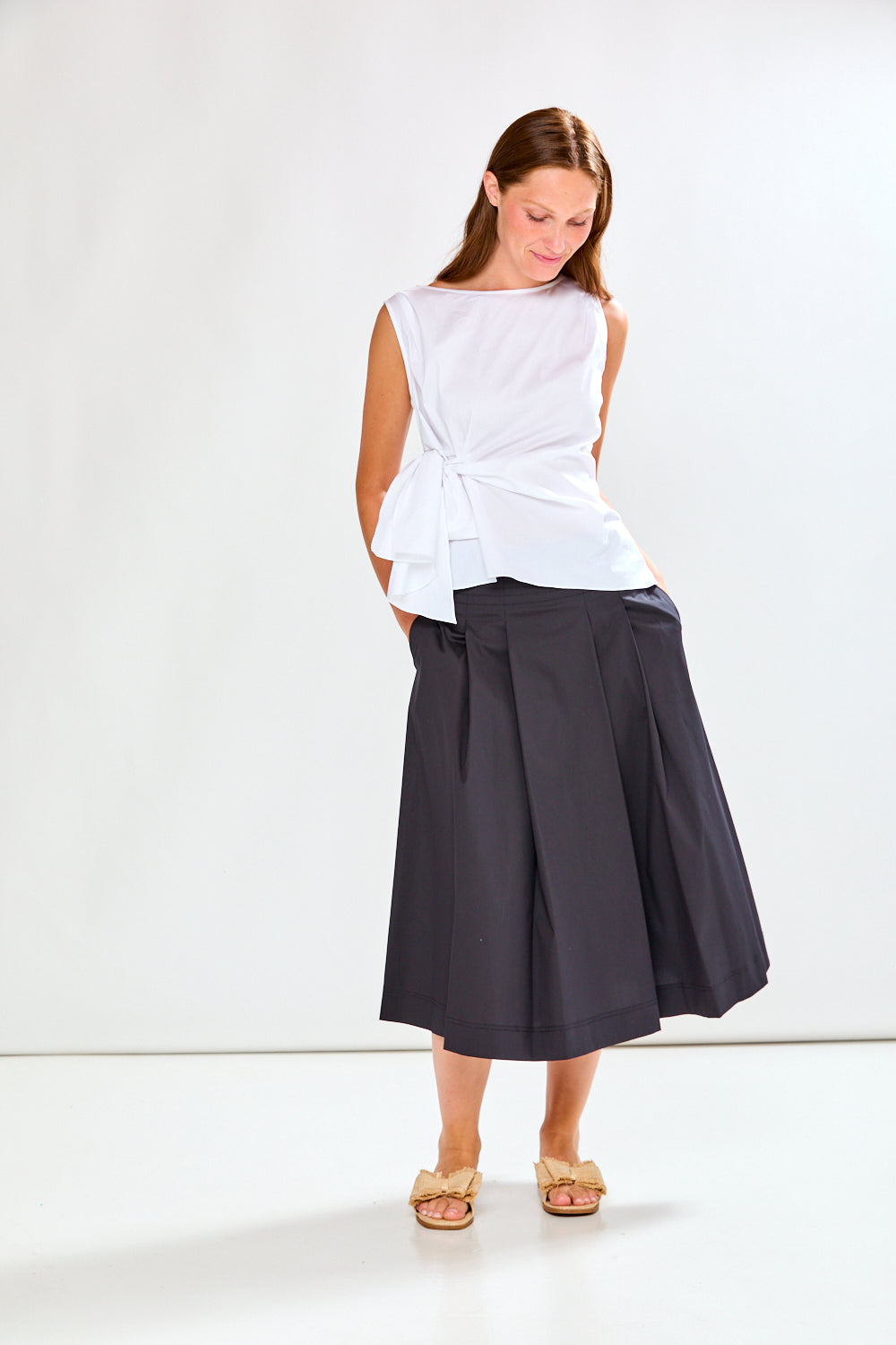 Woman wearing a white top and dark gray skirt on a white background