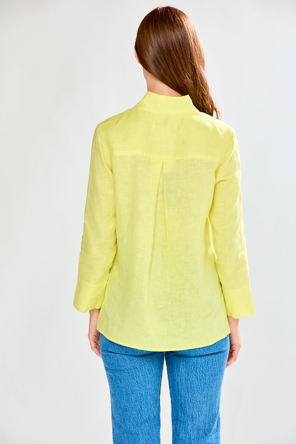 Woman wearing a sunflower and blue jeans against a white background