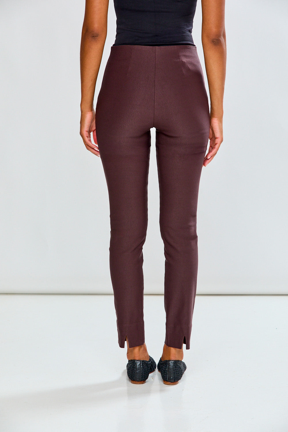 Person wearing espresso pants and black top on a white background