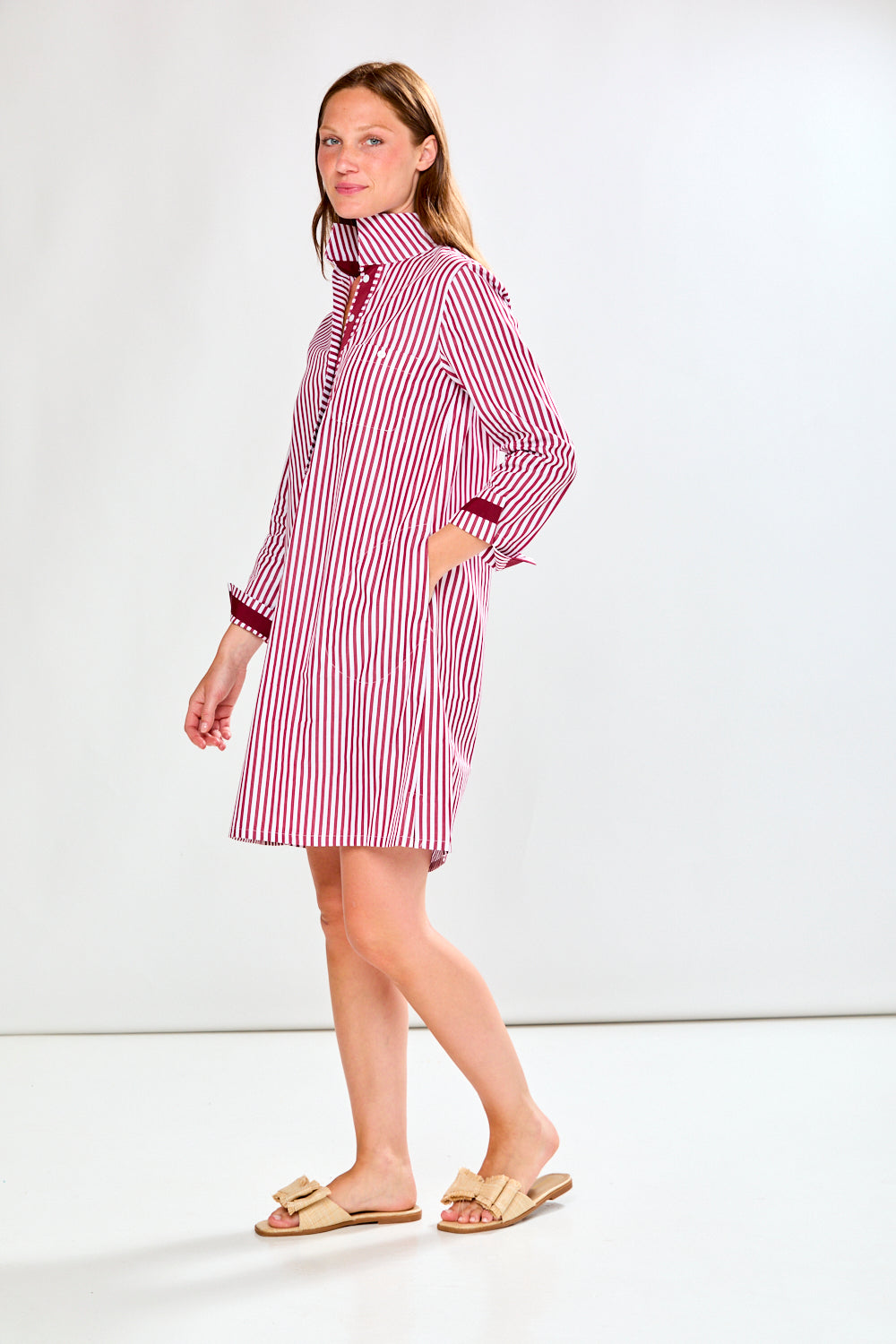 Woman wearing a raisin and white striped dress on a white background