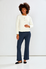 Woman wearing a white blouse and navy pants against a white background