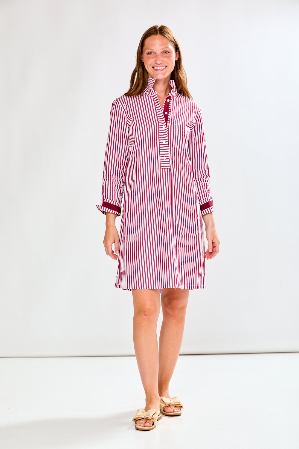 Woman wearing a raisin and white striped dress on a white background