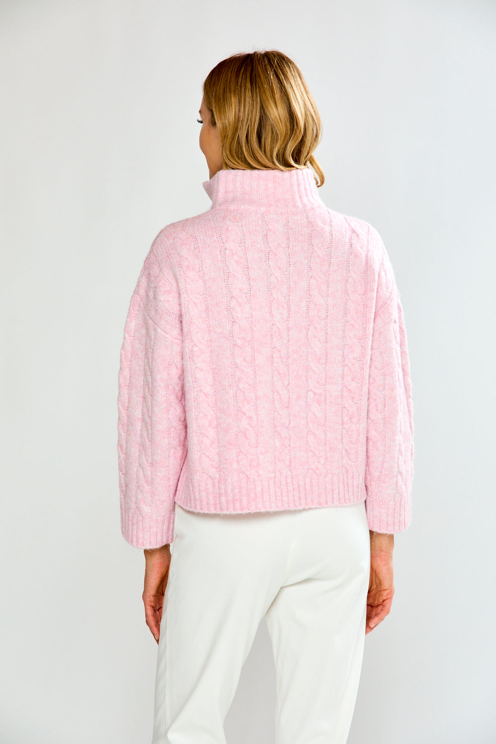 Woman wearing a pink pullover with a zipper on a white background