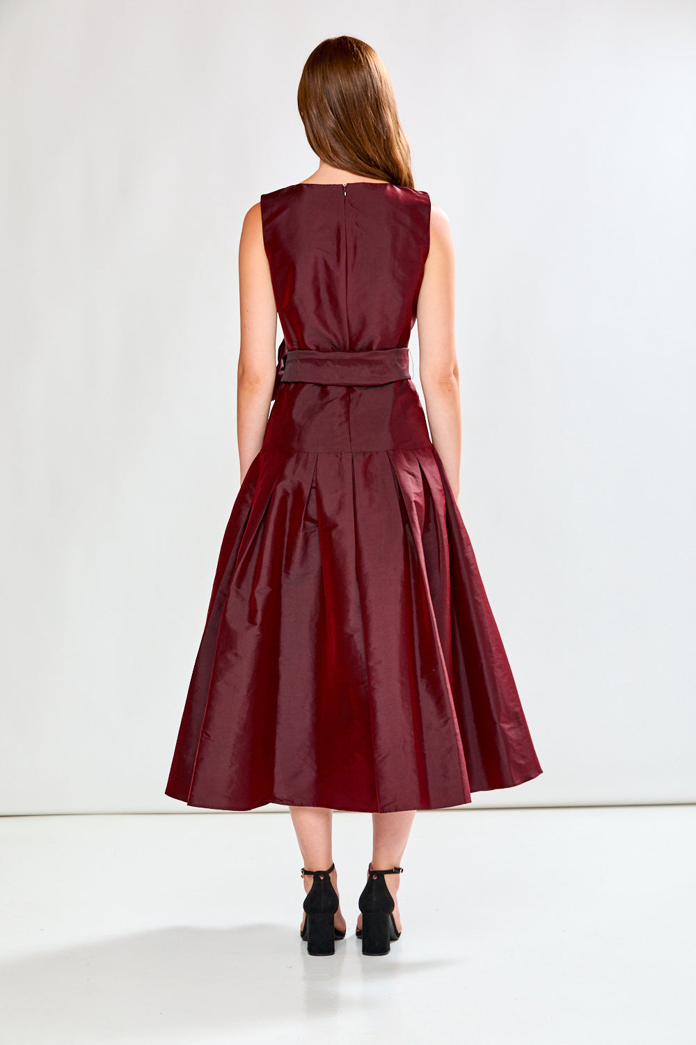 Woman wearing a burgundy dress with a belt on a white background