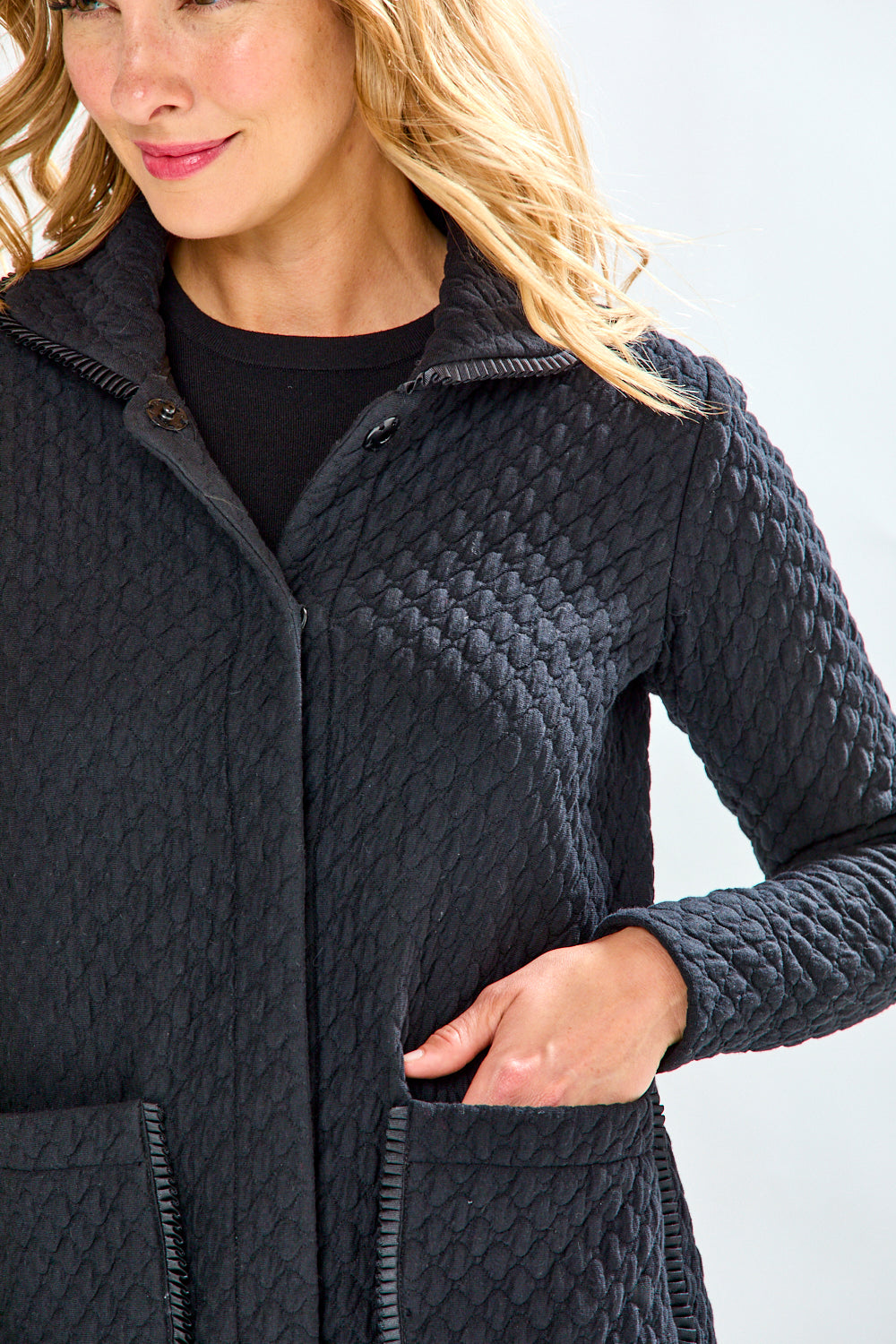 Woman wearing a black quilted jacket and plaid pants on a white background