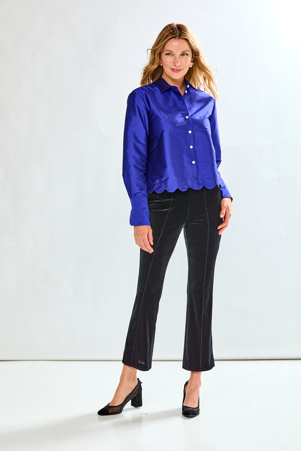 Woman wearing a blue blouse and black pants on a white background