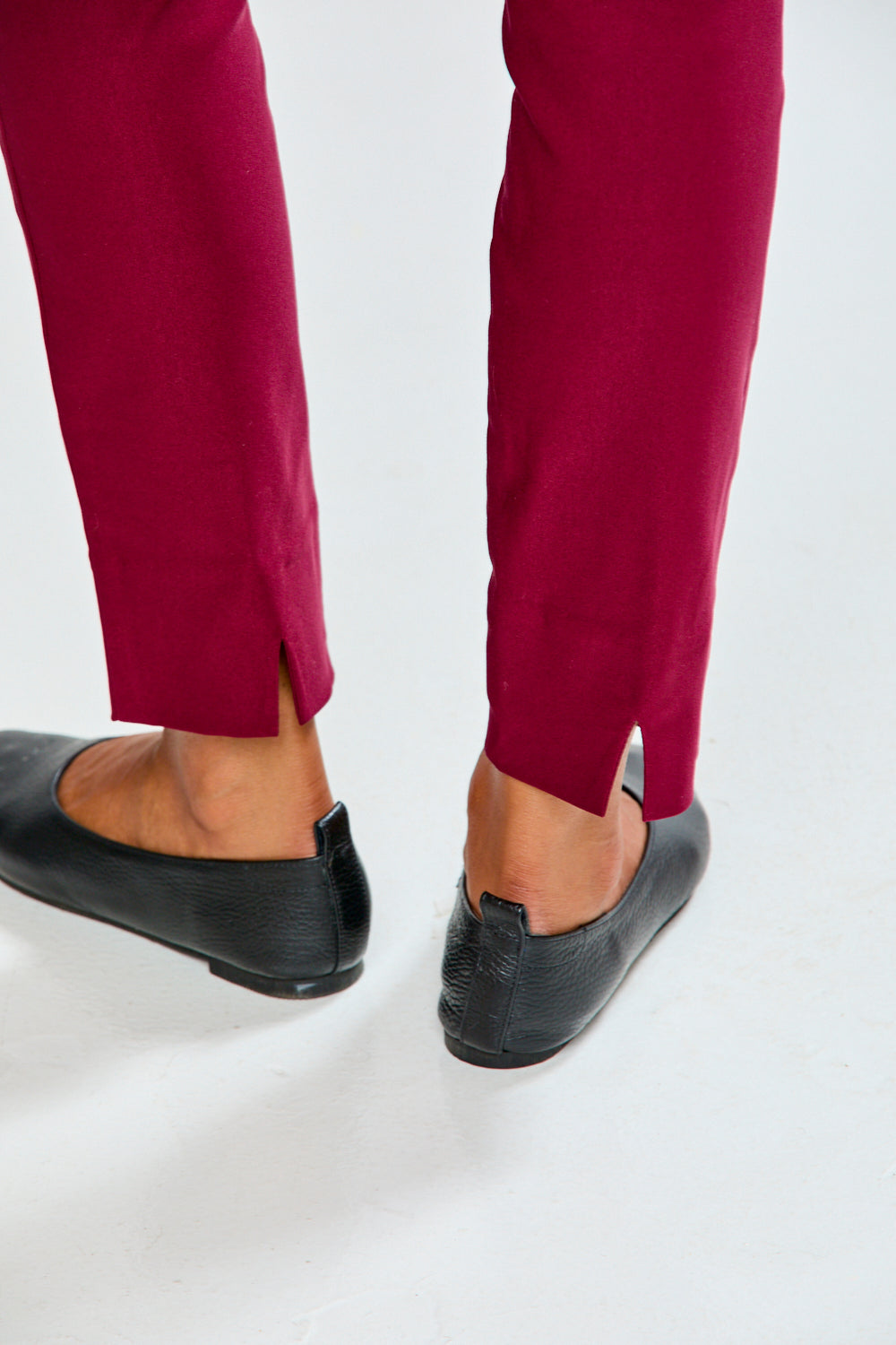 Person wearing raisin pants and black shoes on a white background