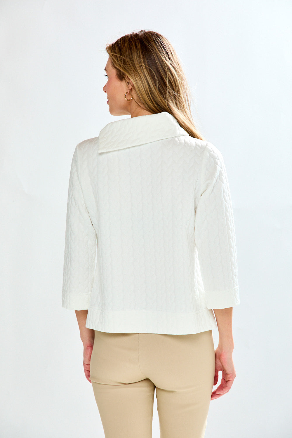 Woman wearing a white jacket and beige pants on a white background