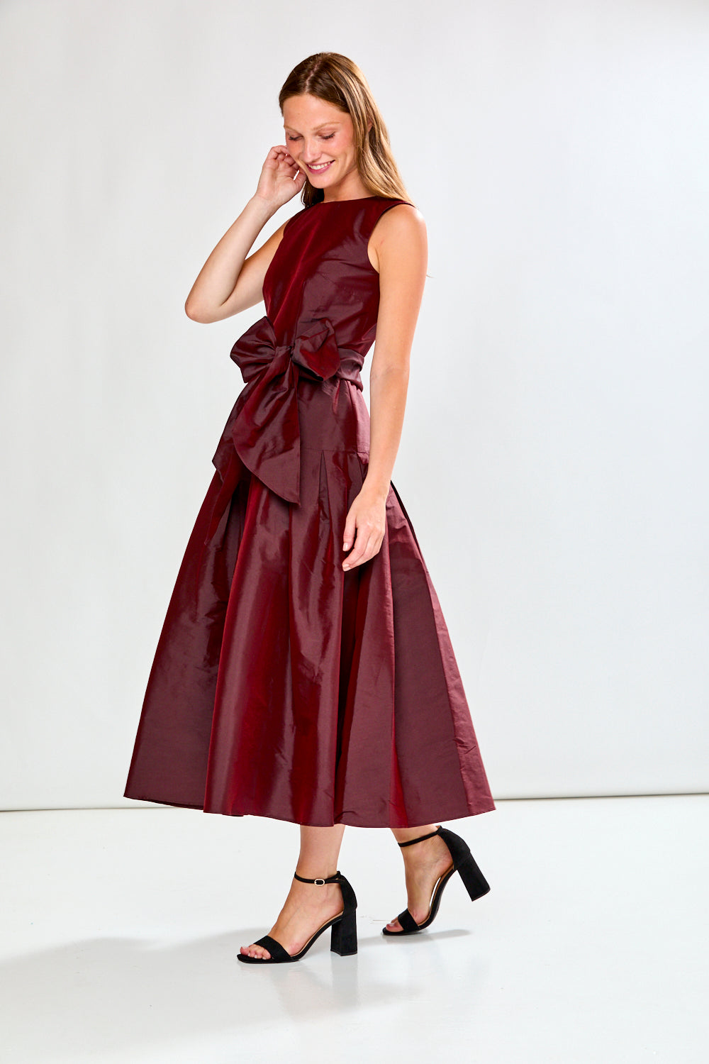 Woman wearing a burgundy dress with a bow detail on a white background