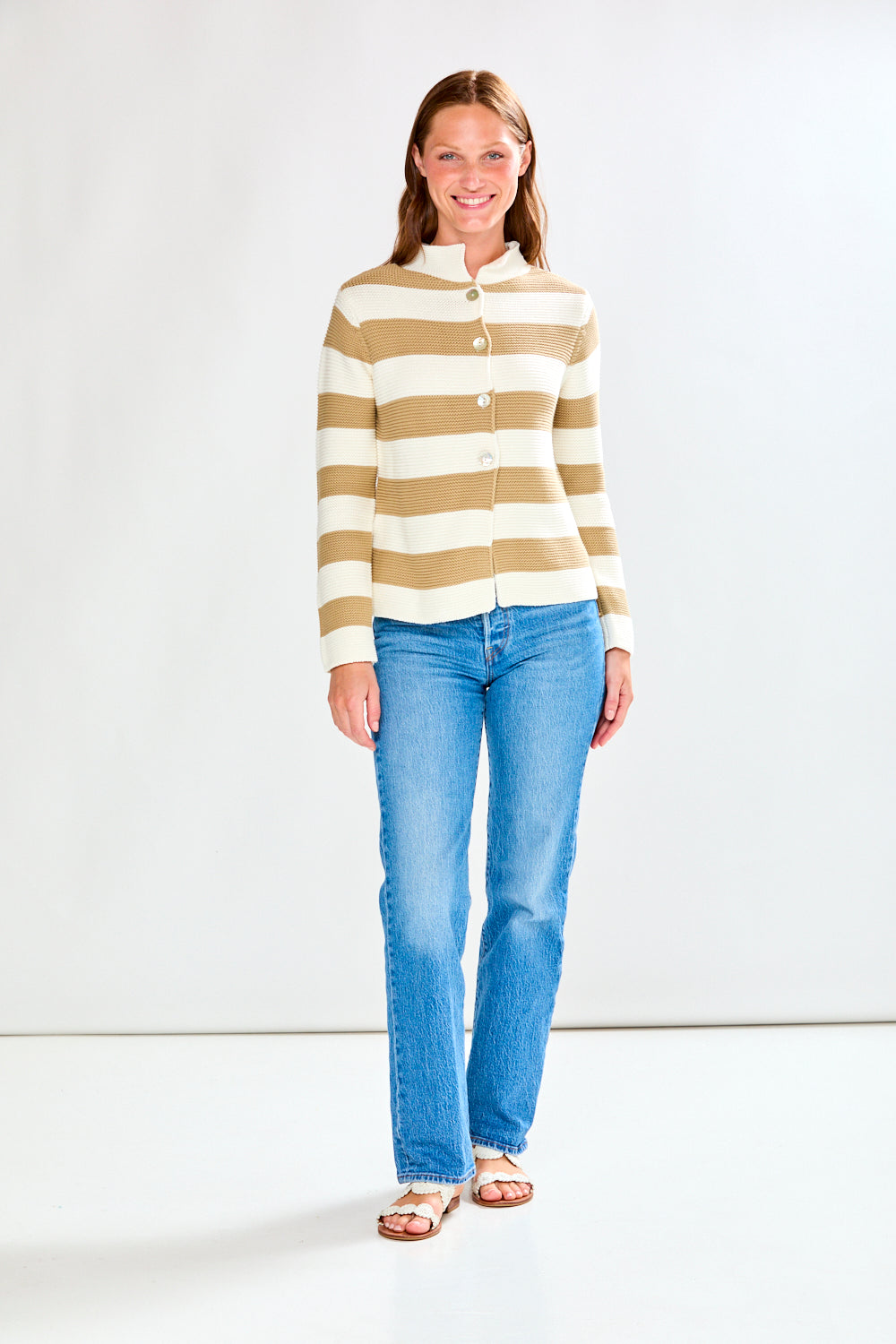 Woman wearing a striped shirt and jeans against a white background