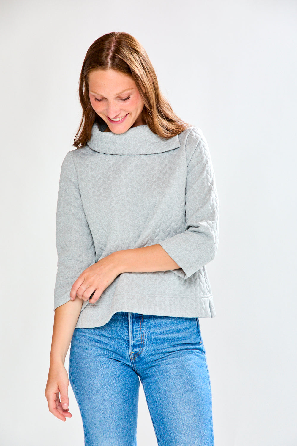 Woman wearing a gray sweater and blue jeans on a white background