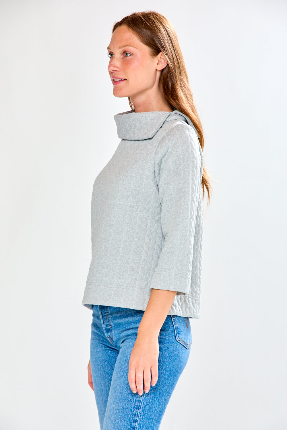 Woman wearing a light gray jacket and blue jeans on a white background