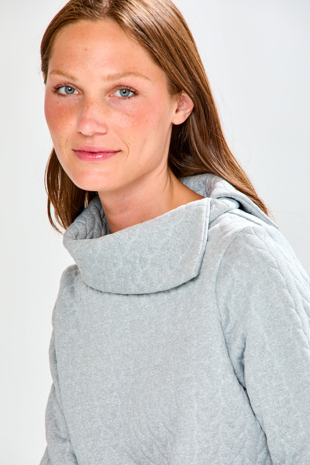 Woman wearing a gray hoodie against a white background