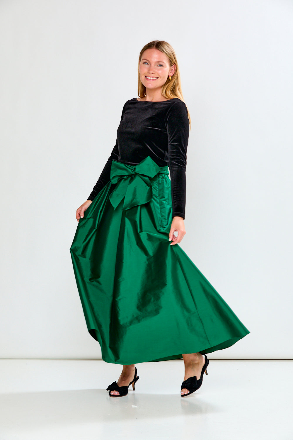 Woman wearing a Black top and Emerald skirt on a white background