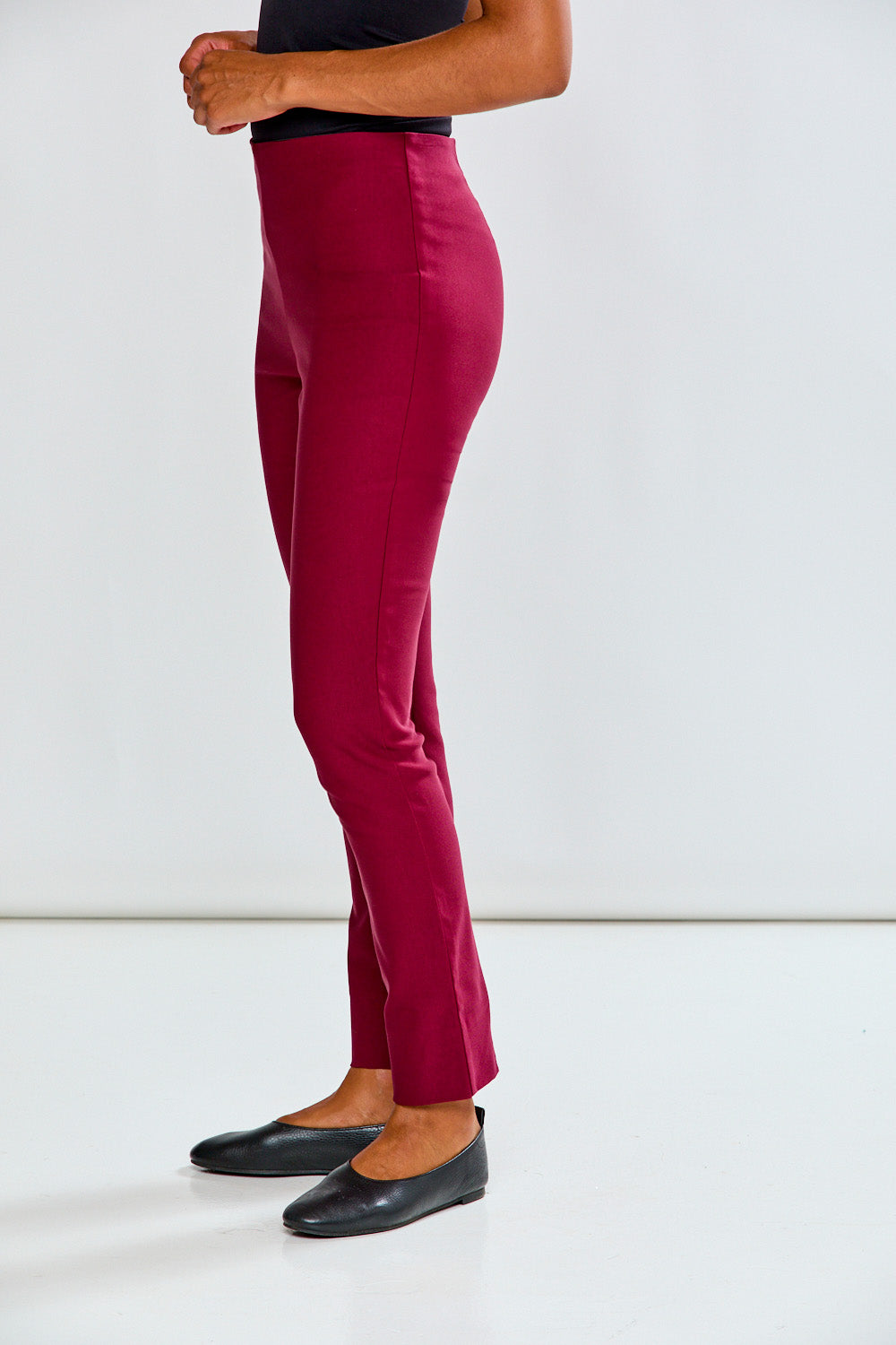 Person wearing raisin pants and black shoes on a white background