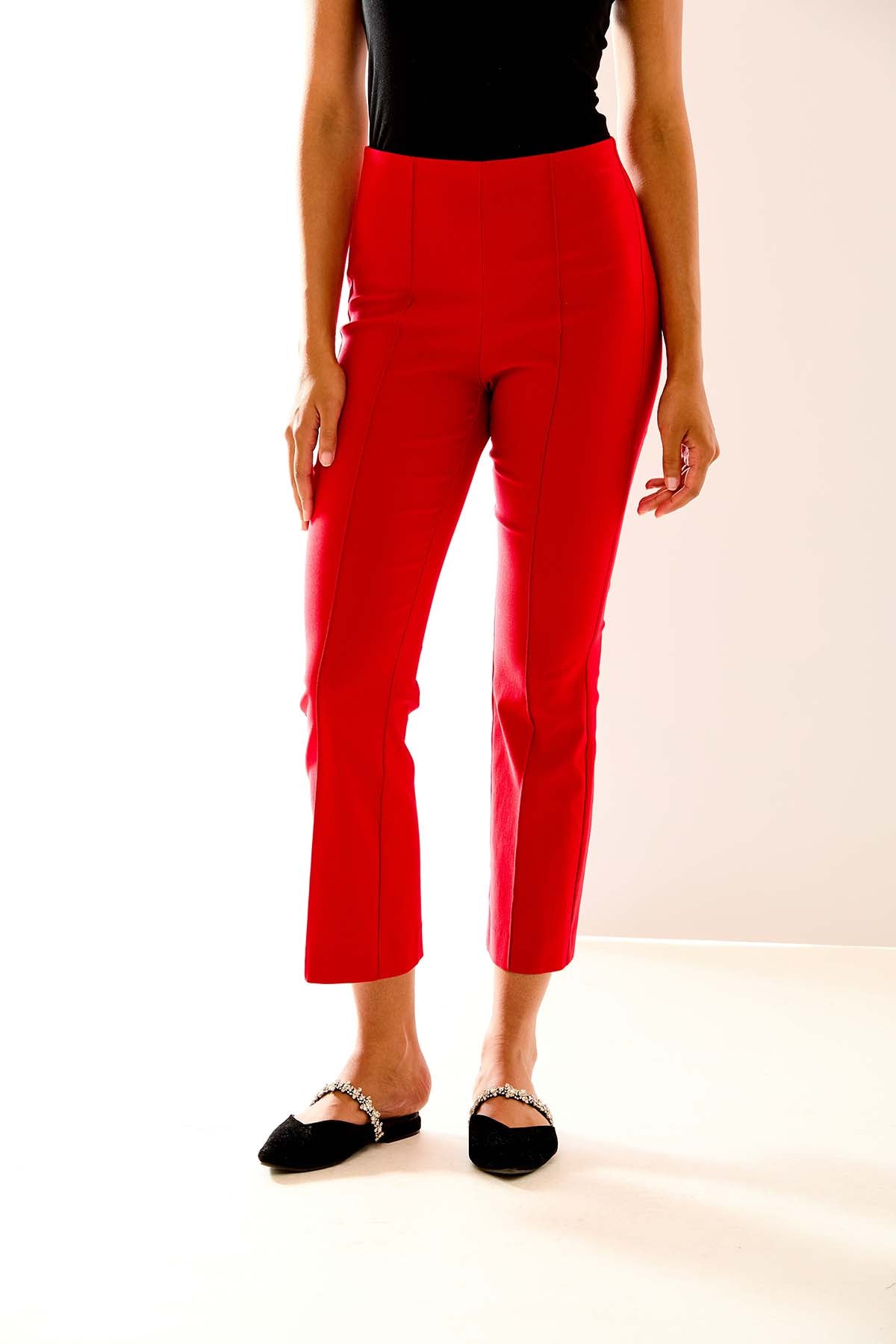 Person wearing red pants and black shoes on a white background