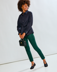Woman wearing a black shirt and green pants against a white background