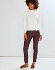 Woman wearing a white sweater and brown pants against a white background
