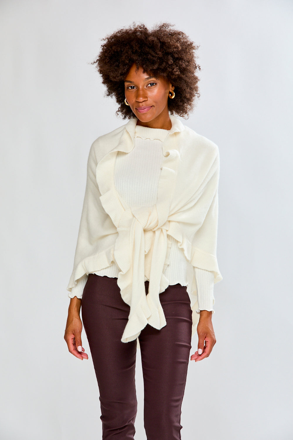 Woman wearing a white blouse with a tie front design on a plain background
