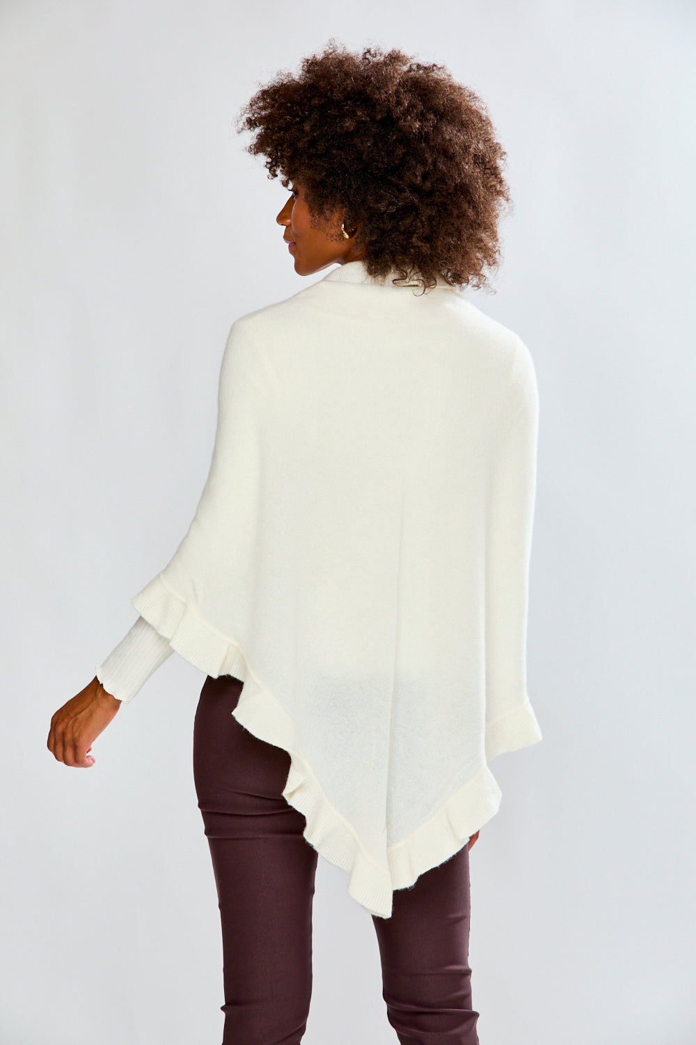 Person wearing a white poncho over a dark outfit on a plain background