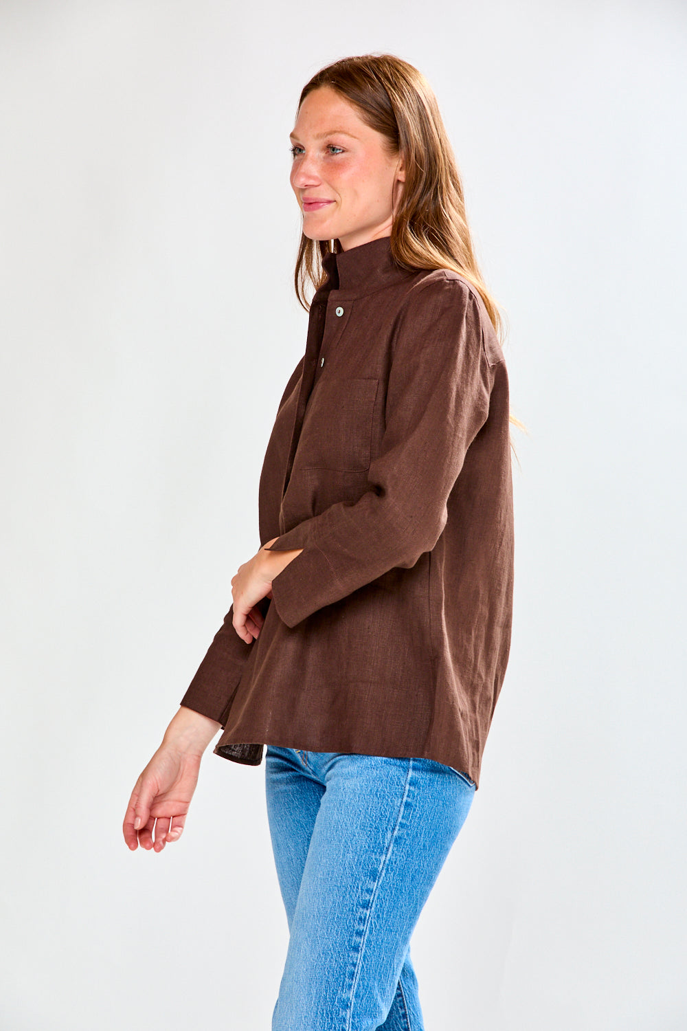 Woman wearing a brown jacket and blue jeans on a white background