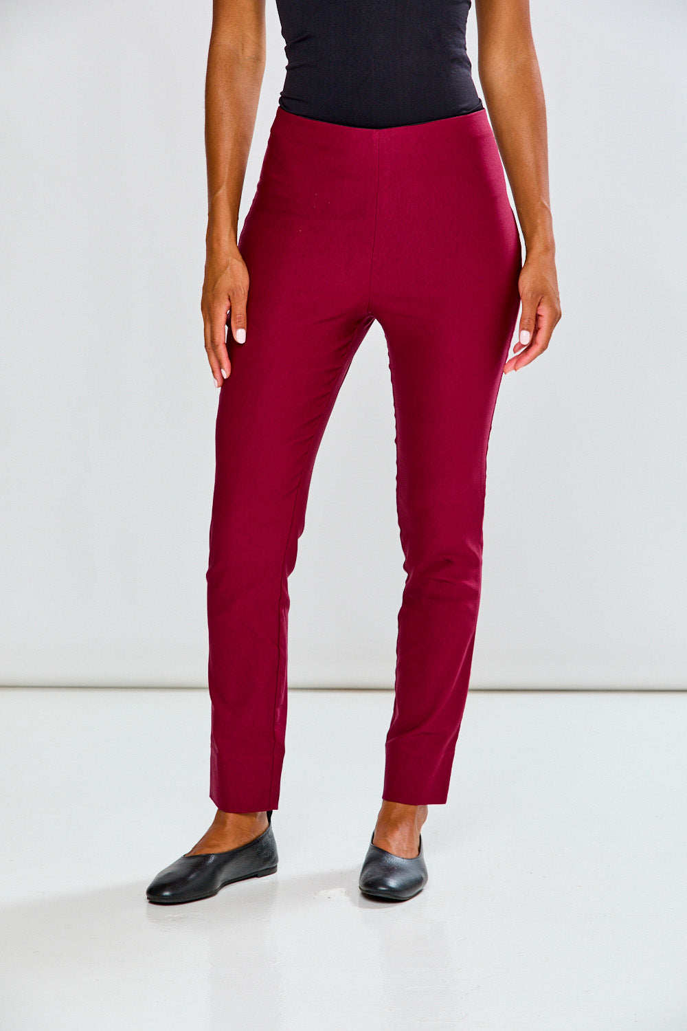 Person wearing raisin pants and black shoes on a white background