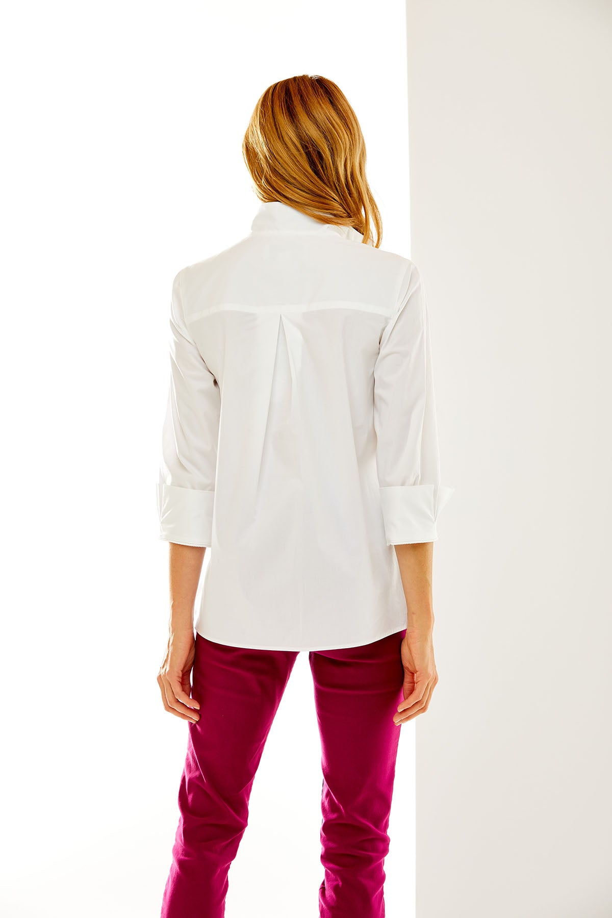 Woman wearing a white shirt and pink pants on a white background