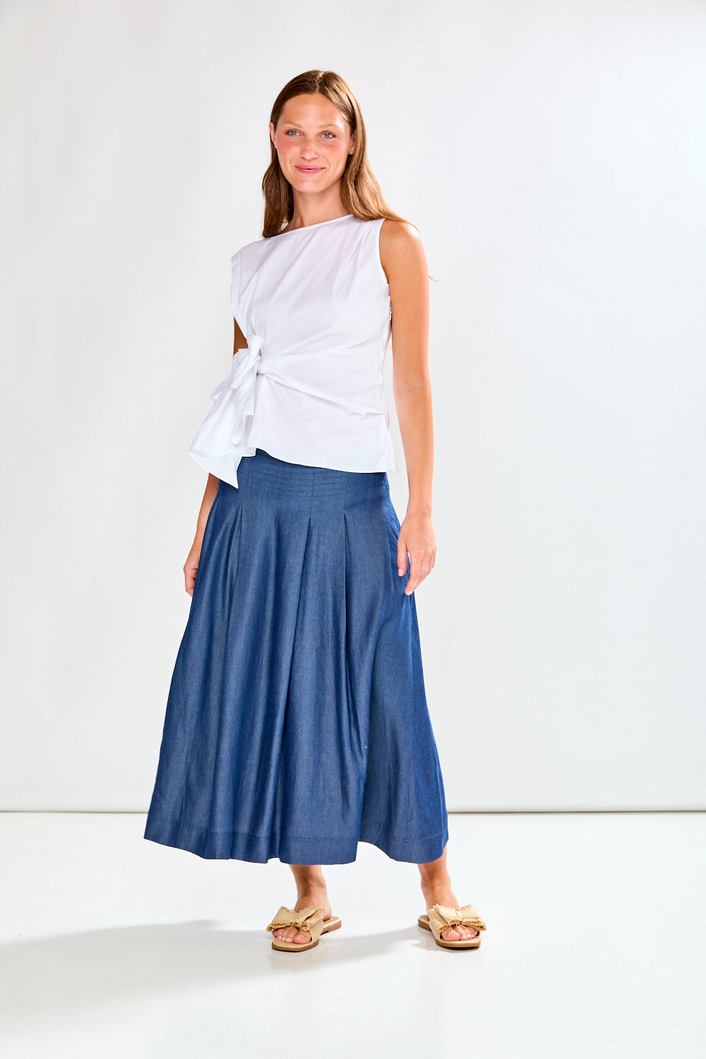Woman wearing a white top and blue skirt on a white background