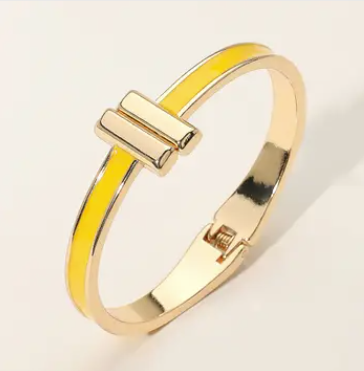Gold bracelet with a yellow accent on a light beige background
