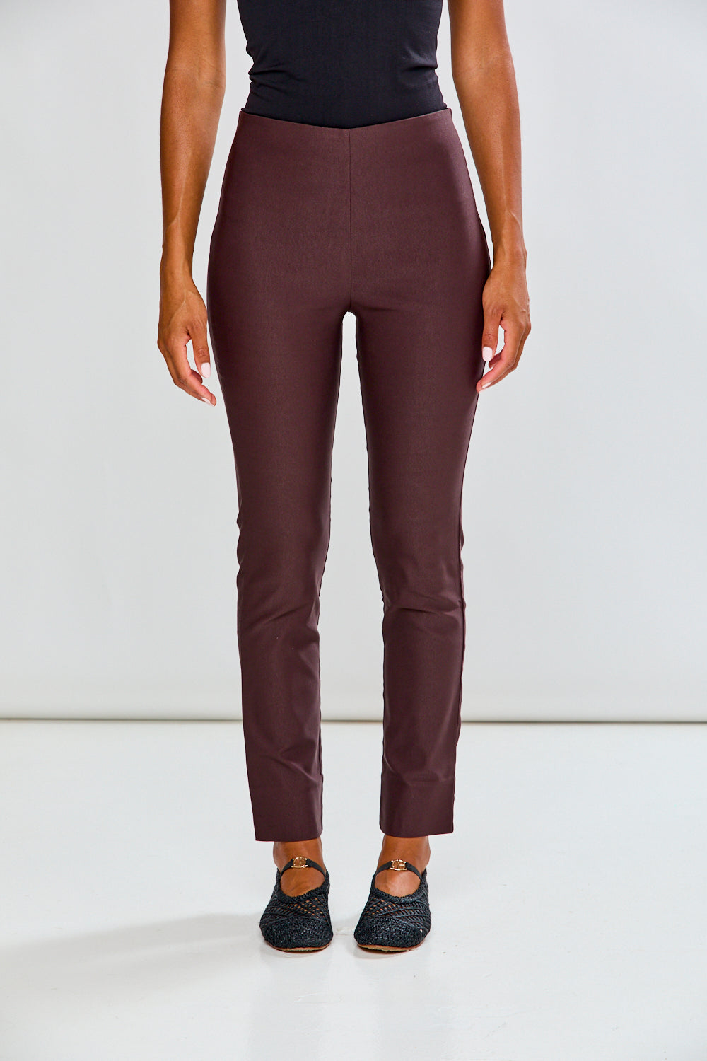 Person wearing espresso pants and black top on a white background